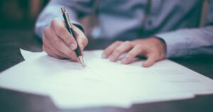 書類にサインする場面｜建設業許可の要件確認